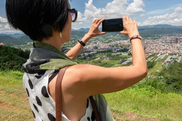 アジアの女性は丘の上に立つ青空の下で写真を撮る — ストック写真
