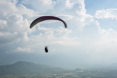 Kasabada beyaz bulutlar, Puli, Tayvan 'da mavi gökyüzünde renkli paraşütler.
