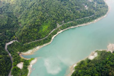 Mingtan Reservoir, Shuili kasabası, Nantou, Tayvan 'daki göl kenarındaki ağaçların olduğu bir yol manzarası.
