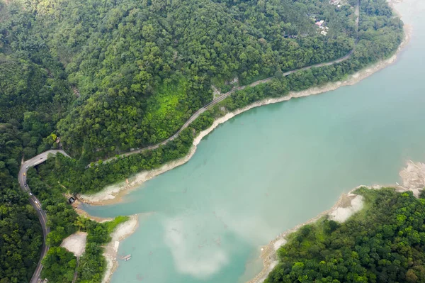 Mingtan Reservoir, Shuili kasabası, Nantou, Tayvan 'daki göl kenarındaki ağaçların olduğu bir yol manzarası.