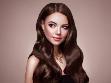 Uzun sağlıklı ve parlak kıvırcık saçlı esmer kız. Bakım ve güzellik. Güzel Model kadınla dalgalı saç modeli. Makyaj ve takı