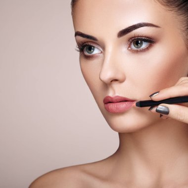 Güzel kadın dudaklarına ruj ile boyar. Güzel bir kadın yüzü. Makyaj ayrıntı. Güzellik modeli mükemmel deri ile. Kırmızı dudaklar ve tırnaklar manikür