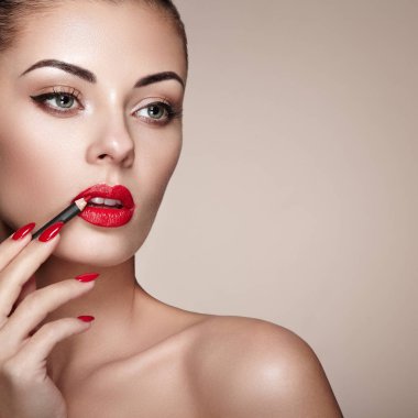 Güzel kadın dudaklarına ruj ile boyar. Güzel bir kadın yüzü. Makyaj ayrıntı. Güzellik modeli mükemmel deri ile. Kırmızı dudaklar ve tırnaklar manikür