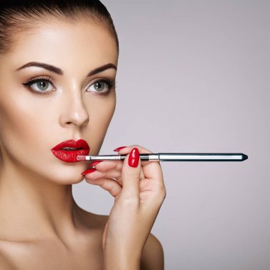 Güzel kadın dudaklarına ruj ile boyar. Güzel bir kadın yüzü. Makyaj ayrıntı. Güzellik modeli mükemmel deri ile. Kırmızı dudaklar ve tırnaklar manikür