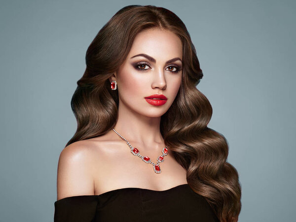 Брюнетка с длинными здоровыми и блестящими вьющимися волосами. Уход и красота. Образцовая женщина с волнистым хайрстиком. Макияж и черное платье