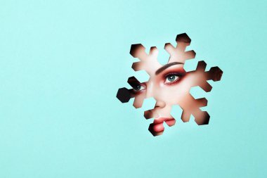 Güzellik makyaj olan güzel bir kadın yüzü. Uzantısı kirpik, yeşil gözlü güzel pembe gölgeler. Kar tanesi. Noel desenleri. Mavi kağıt