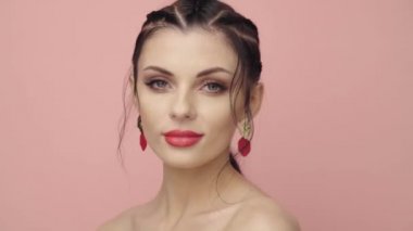 Saçları örgülü esmer kız. Modelin yakın plan portresi. Mükemmel makyaj. Güzel saçlar, moda videoları. Mücevherleri olan güzel kadın. 4k 25fps