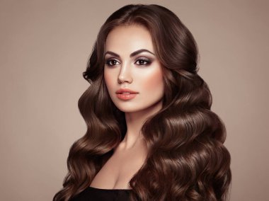 Uzun, sağlıklı ve kıvırcık saçlı esmer kız. Bakım ve Güzellik. Dalgalı saçlı güzel model kadın. Makyaj ve Mücevher