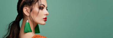 Mükemmel makyajlı esmer kız. Kıvırcık saçlı güzel bir model kadın. Bakım ve güzellik ürünleri. Saçları örgülü bir kadın. Mücevherleri olan bir model. Turkuaz arkaplan