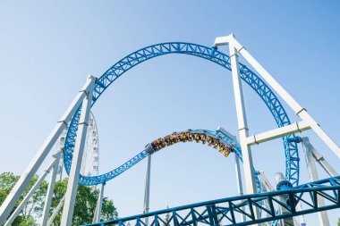 Mavi gökyüzüne karşı lunapark treni. Lunaparktaki lunaparkta hız treni. Eğlence parkında neşeli eğlenceler.