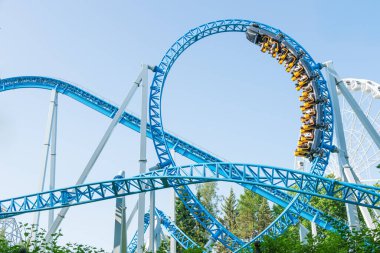 Mavi gökyüzüne karşı lunapark treni. Lunaparktaki lunaparkta hız treni. Eğlence parkında neşeli eğlenceler.