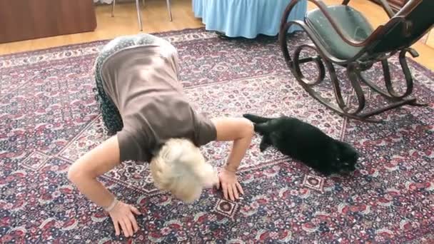 Μια Ηλικιωμένη Γυναίκα Κάνει Ασκήσεις Γάτα Βρίσκεται Δίπλα Της — Αρχείο Βίντεο
