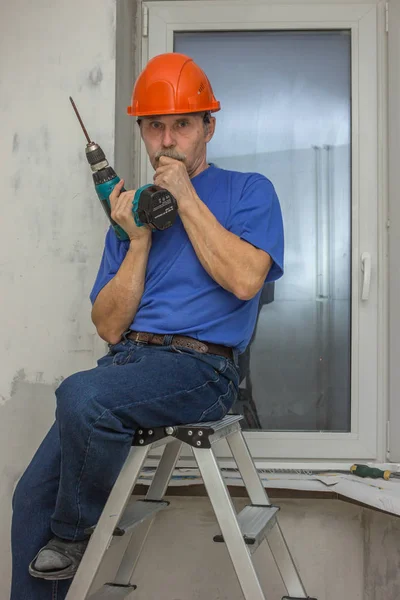 Elderly worker sits at a loss on a ladder — Stock Photo, Image