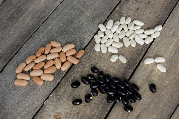 Seeds of brown, white and black beans scattered on table — Stock Photo, Image