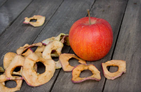 One whole apple and scattered dried apple slices on table