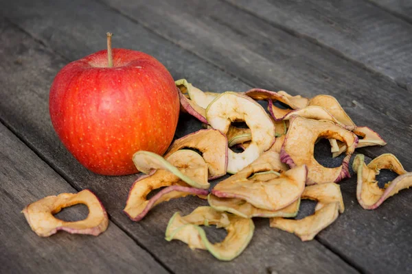 Одно целое яблоко и сушеные яблочные ломтики на столе — стоковое фото