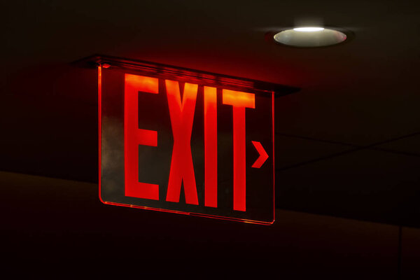 red lit exit sign on black background
