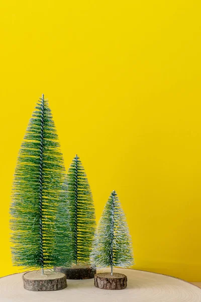 Weihnachtsschmuck Drei Tannenbäume Vor Gelbem Hintergrund — Stockfoto