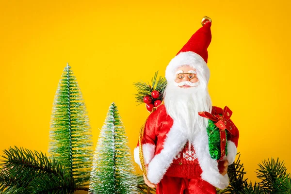 一个圣诞老人图与冷杉树在黄色背景 — 图库照片