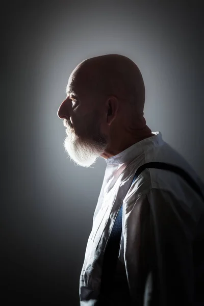 profile of old man with beard on grey background