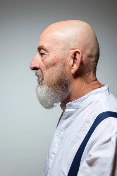 profile of old man with beard on grey background