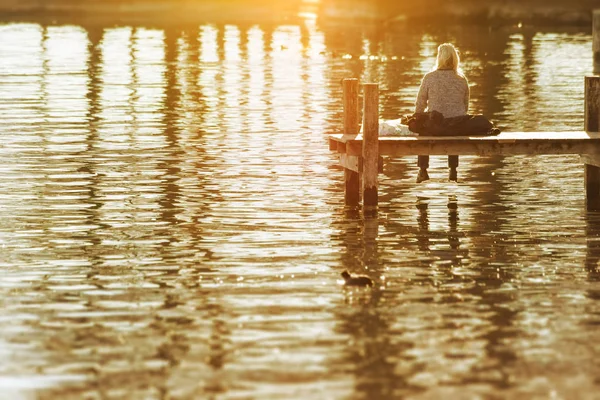 A woman sitting on a wooden jetty at Starnberg Lake Tutzing Bava — Stock Photo, Image