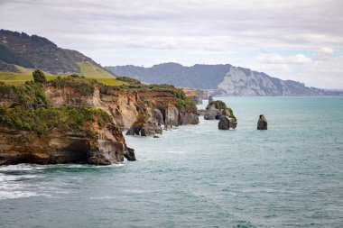 deniz kıyısı kayaları ve Taranaki Dağı, Yeni Zelanda