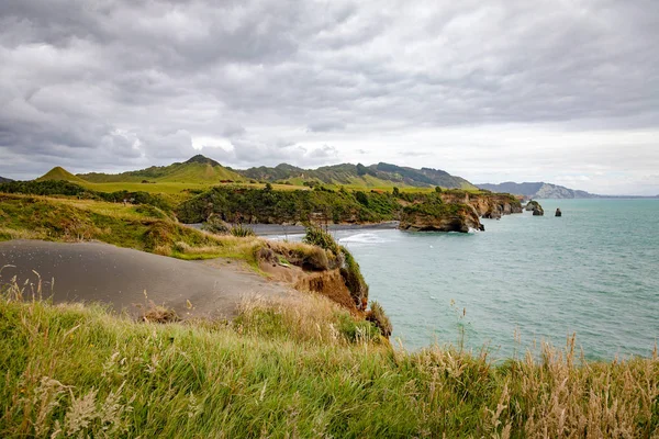 Rocas de la orilla del mar y el monte Taranaki, Nueva Zelanda — Foto de Stock