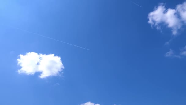 青空の背景に白い雲の中を飛ぶ飛行機の時間経過 — ストック動画