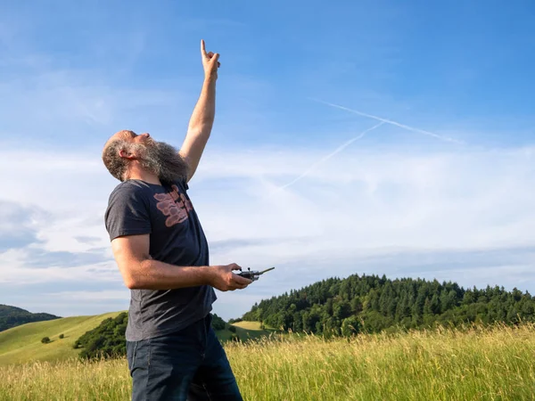 Man pointing up to his drone in the sky — Stock Photo, Image