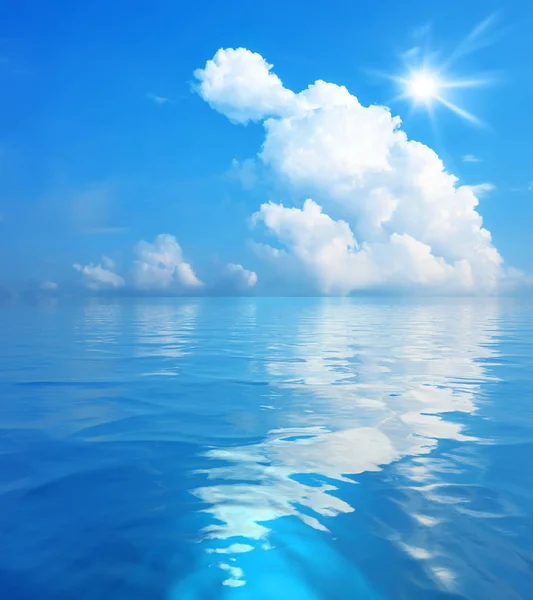 Голубое небо с белыми облаками и солнцем над морем — стоковое фото