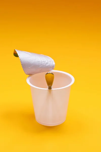 Copo de iogurte limpo vazio com colher em um fundo laranja — Fotografia de Stock