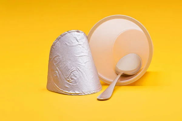 Copo de iogurte limpo vazio com colher em um fundo laranja — Fotografia de Stock