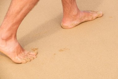 Islak kumda çıplak ayak bir erkek resmi.