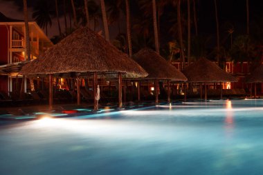 Tropical resort lighted swimming pool at night clipart