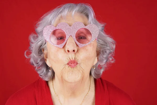 滑稽的奶奶与心脏形状的眼镜吹吻 — 图库照片#