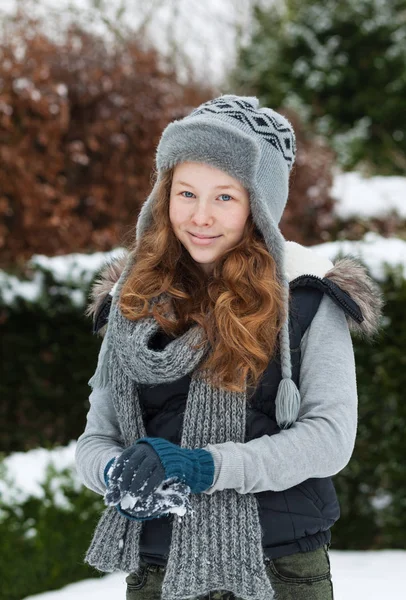 Rubia adolescente chica haciendo una bola de nieve en el parque nevado Imagen de archivo