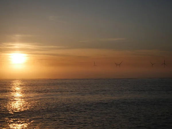 海で夕日を背景に風力タービン — ストック写真