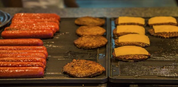 Perros calientes y hamburguesas de queso en una parrilla — Foto de Stock