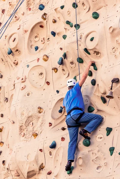 Человек среднего возраста в синей стене для скалолазания — стоковое фото