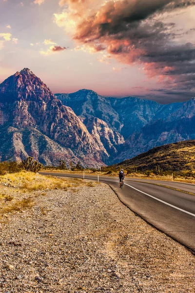 Rider Cycling on Road Through Desert Toward Mountains — Stock Photo, Image