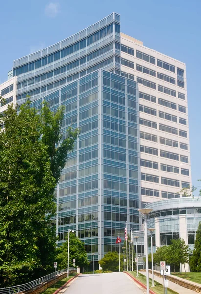 Torre de oficina blanca y azul más allá de los árboles Imagen de archivo