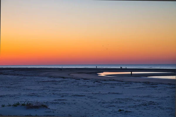 Persone che camminano sulla spiaggia sotto la luce dell'alba — Foto Stock