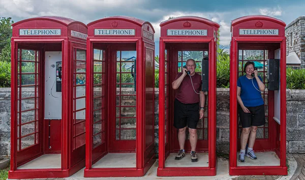 Pareja jubilada en cabinas telefónicas rojas — Foto de Stock