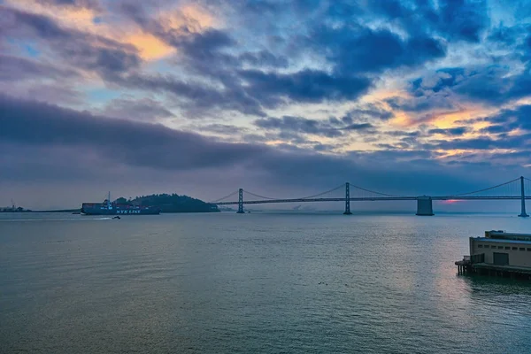 Vrachtschip bij Bay Bridge bij zonsopgang — Stockfoto