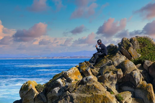 Hombre sentado en rocas del Pacífico — Foto de Stock