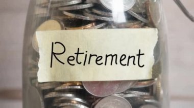 Cam kavanoz emeklilik etiket, mali kavramı ile para çıktı. Ahşap antika arka plan dramatik ışık ile. 4 k görüntüleri video kaydırma veya yakınlaştırma.