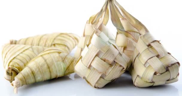 Ketupat は東南アジアでお祭りのシーズン中に地元の珍味です Ketupat 若いココナッツから作られた自然米ケーシングを伝統的なマットの背景に米を調理に残します 映像ビデオ — ストック動画