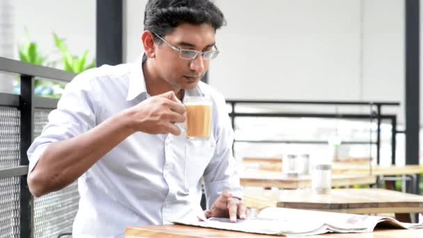 昼休み食堂でカップの熱いミルクティーを飲みながら新聞を読んでアジア インド ビジネスの男性 — ストック動画