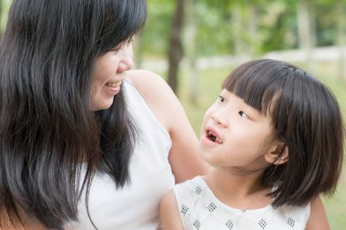 Mutlu anne ve kızı yeşil park adlı bağlar. Asya aile açık havada etkinlik.